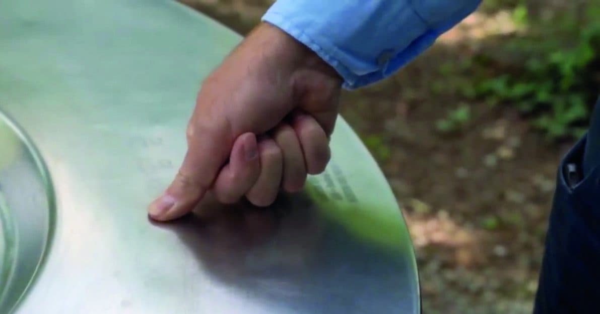 Un doigt active une icône tactile gravée sur le plateau en inox